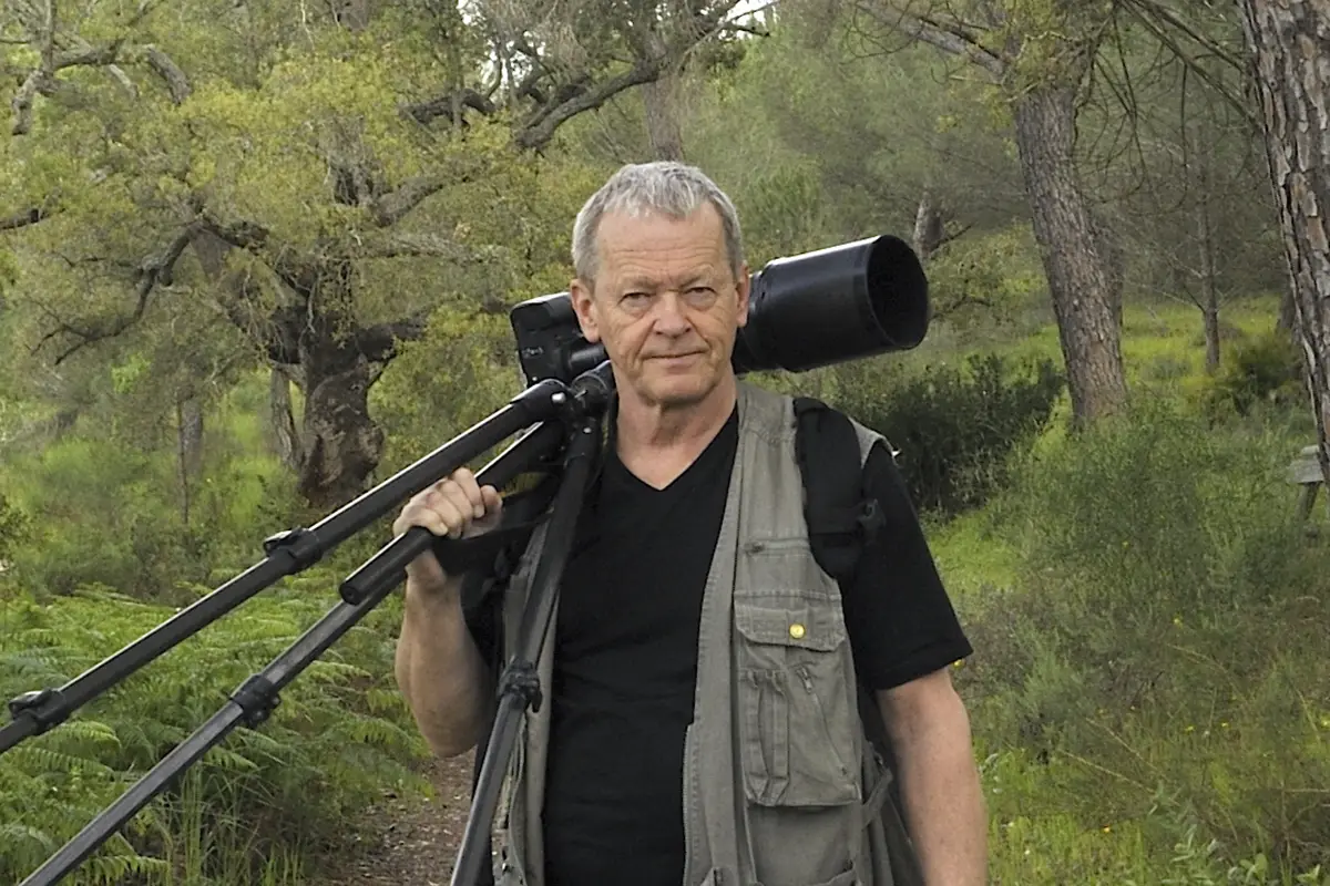Naturfotografen Göran Gustafsson med sin kamera över axeln.